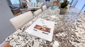 A kitchen with a granite countertop, a white manual, and a dining area with a sofa and chairs. - Quaint Cozy Beach Cape Escape (East Falmouth)