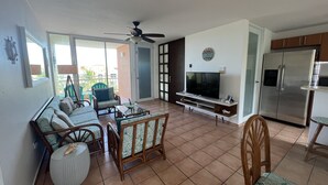 Una sala de estar con sofá, sillas, televisor y refrigerador.