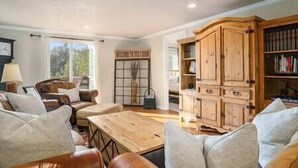 A spacious living room with leather sofas, a wooden coffee table, and a large wooden cabinet with books. - Black Forest Colorado Log Cabin (Black Forest)