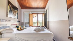 Une chambre d’hôtel avec un lit, un plafond en bois, un tableau, une vue sur le balcon et un sol en marbre.