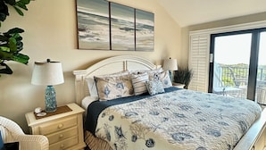 A bedroom with a bed, nightstands, a ceiling fan, a window with a view, and a wall-mounted painting. - Ocean View Beachfront Getaway Directly on St. Augustine Beach.  (St. Augustine Beach)