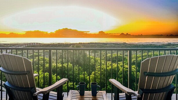 A balcony with two Adirondack chairs facing a sunset over the ocean. - Ocean View Beachfront Getaway Directly on St. Augustine Beach.  (St. Augustine Beach)