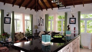 A spacious kitchen with a large island, green curtains, and a ceiling with exposed beams.