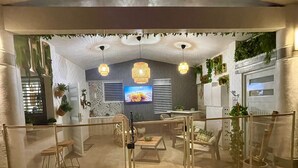Un interior moderno con televisor, muebles de mimbre y plantas decorativas.