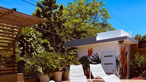 Un área de piscina con sillones de descanso, un flotador y macetas con plantas.