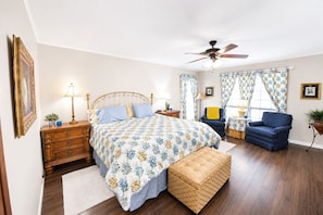 A bedroom with a bed, a chair, a desk, a floor lamp, a ceiling fan, and a window with curtains. - Boutique Farm Stay — Thoughtfully Designed (Georgetown)