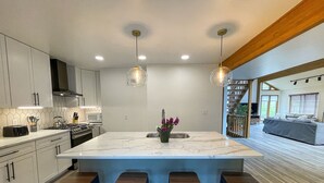 A modern kitchen with a large island, bar stools, and pendant lighting.
