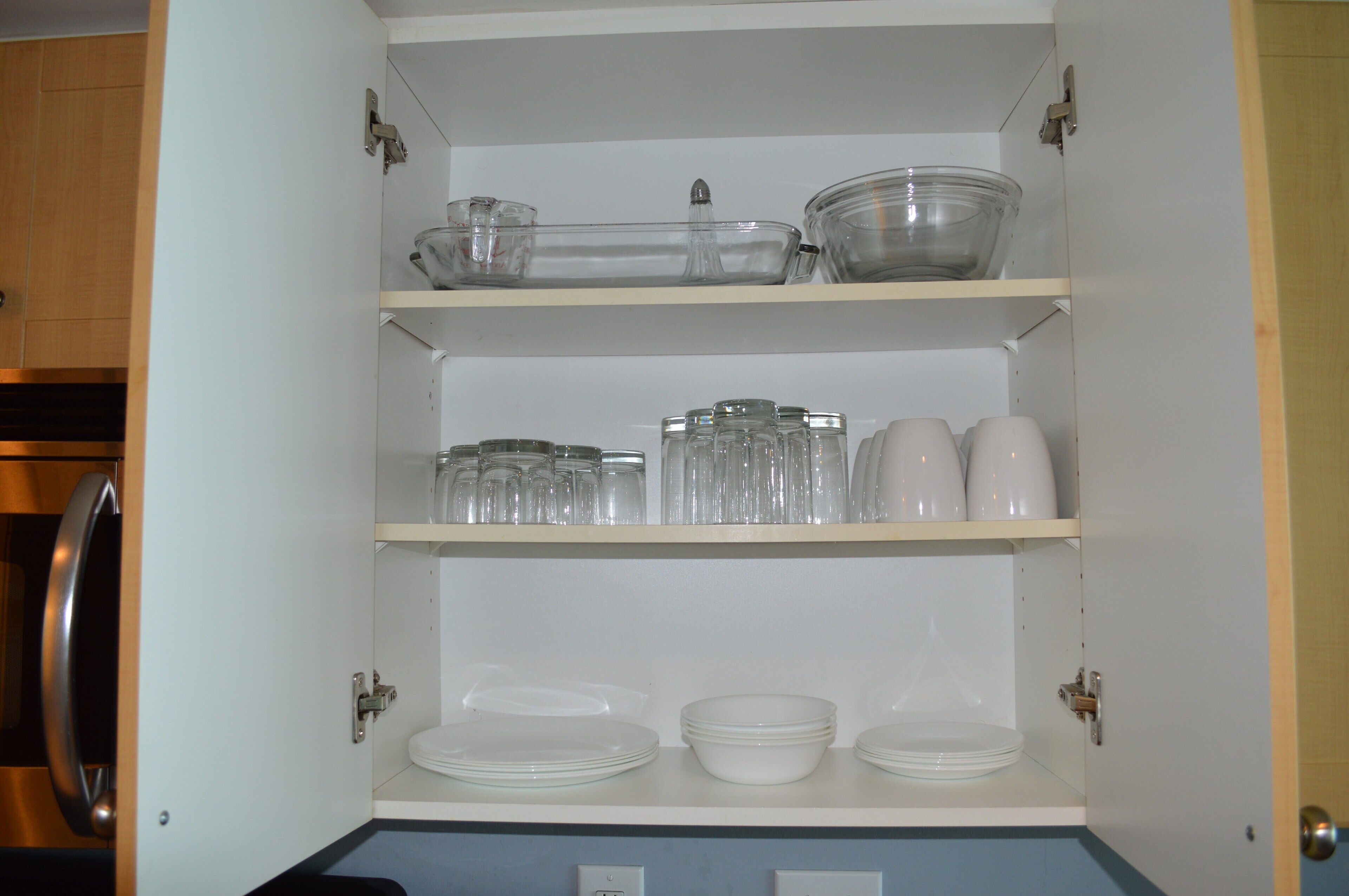 Un armario de cocina con estantes que contienen varios vasos y vajilla.