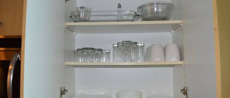 Un armario de cocina con estantes que contienen varios vasos y vajilla.