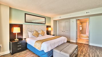 A bedroom with a large bed, bedside tables with lamps, a mirror, and a door leading to a bathroom.