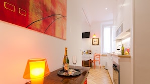 Een moderne keuken met witte kasten, een houten aanrecht en een eethoek met een tafel voor twee personen.