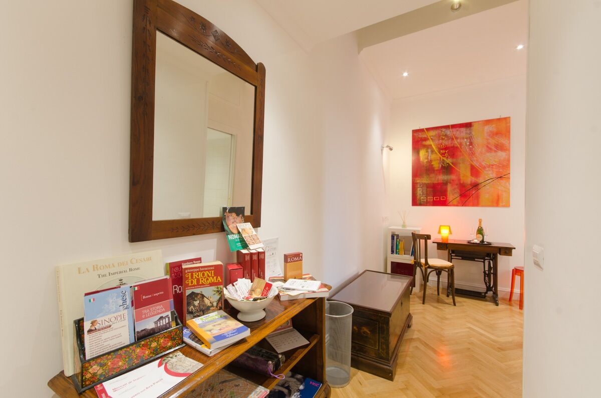 A study area with a wooden desk, books, a mirror, and a red abstract painting.