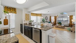 Een moderne keuken met granieten aanrecht, een vaatwasser en een eethoek met een witte tafel en stoelen.