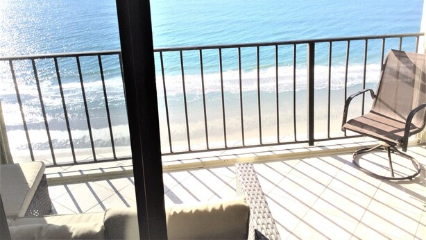 Un balcon avec vue sur l’océan, une chaise et un transat.