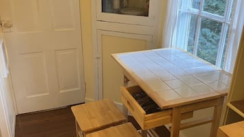 Una cocina con un armario blanco, una ventana y una mesa con azulejos.