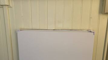 A whiteboard mounted on a wall with a warning sign above it.