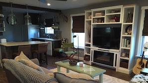 Una sala moderna con un sofá, una mesa de centro y un televisor en un mueble blanco.