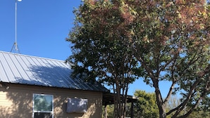 Una pequeña casa con techo metálico, una terraza y mobiliario exterior.