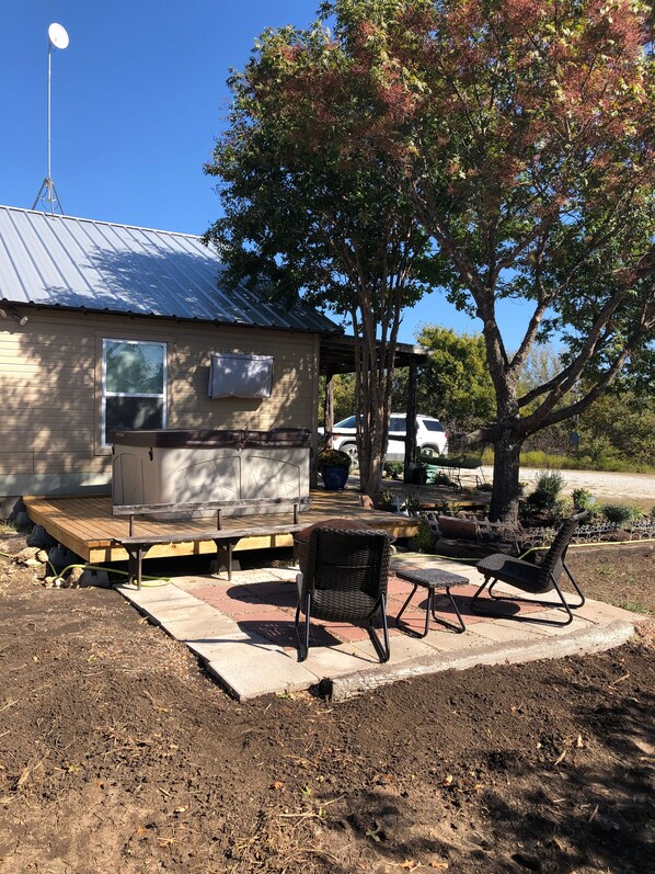 A small house with a metal roof, a deck, and outdoor furniture.