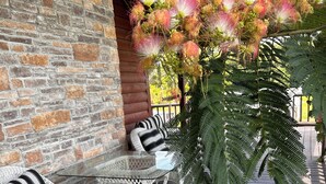 A covered outdoor seating area with wicker furniture and a large fern plant. - Big Cabin on HorseRanch close to MammothCaves,Corvettes,WKU, BeechBend Buc-ees (Smiths Grove)