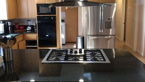 A modern kitchen with stainless steel appliances, wooden cabinets, and a central island with a gas stove.