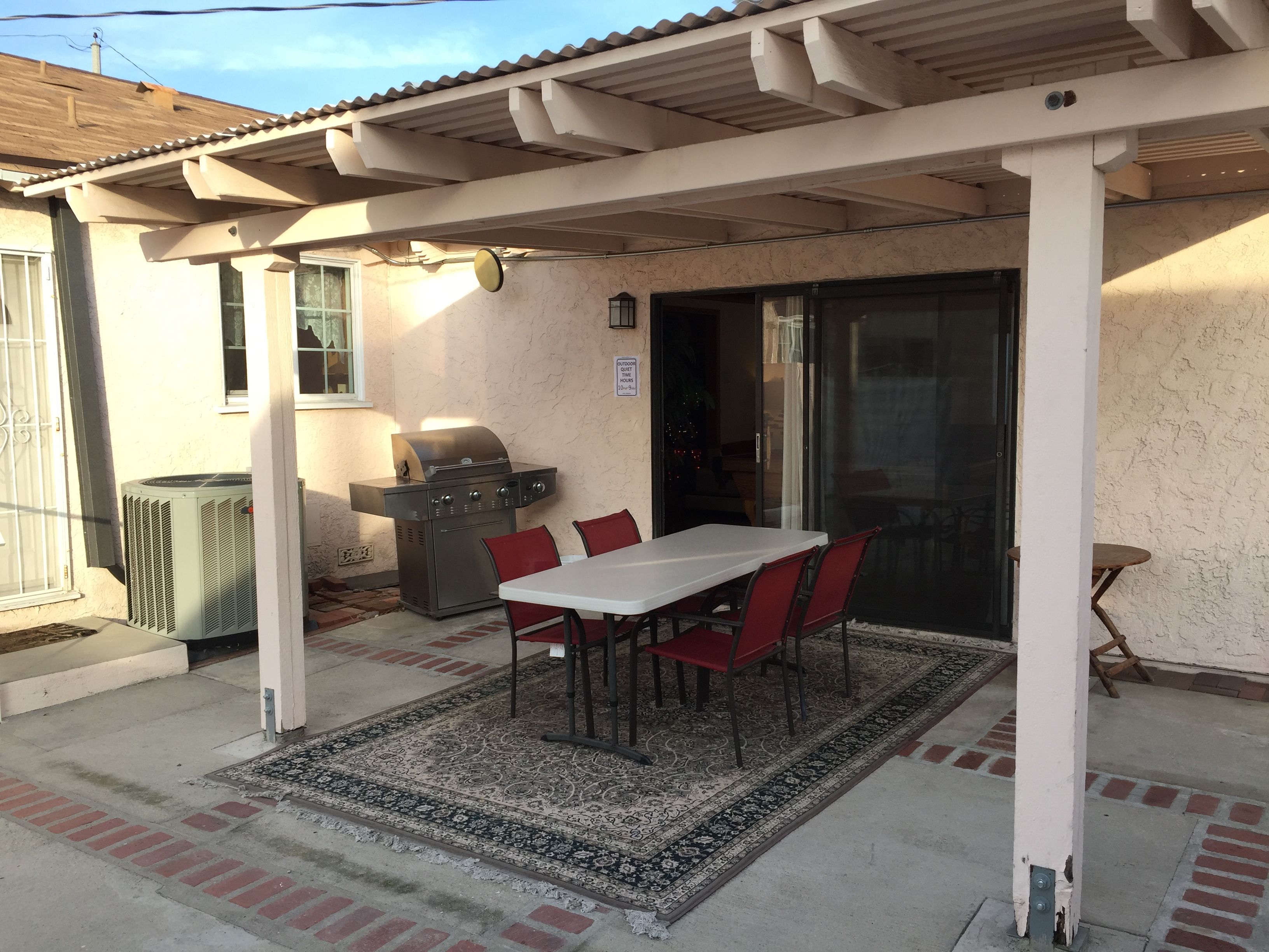 Eine Terrassenausstattung mit Grill, Tisch und Stühlen.