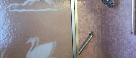A shower with a handheld showerhead and a grab bar.