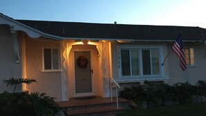 A house with a front porch, a wreath on the door, an American flag, and a number '1316' on the wall.