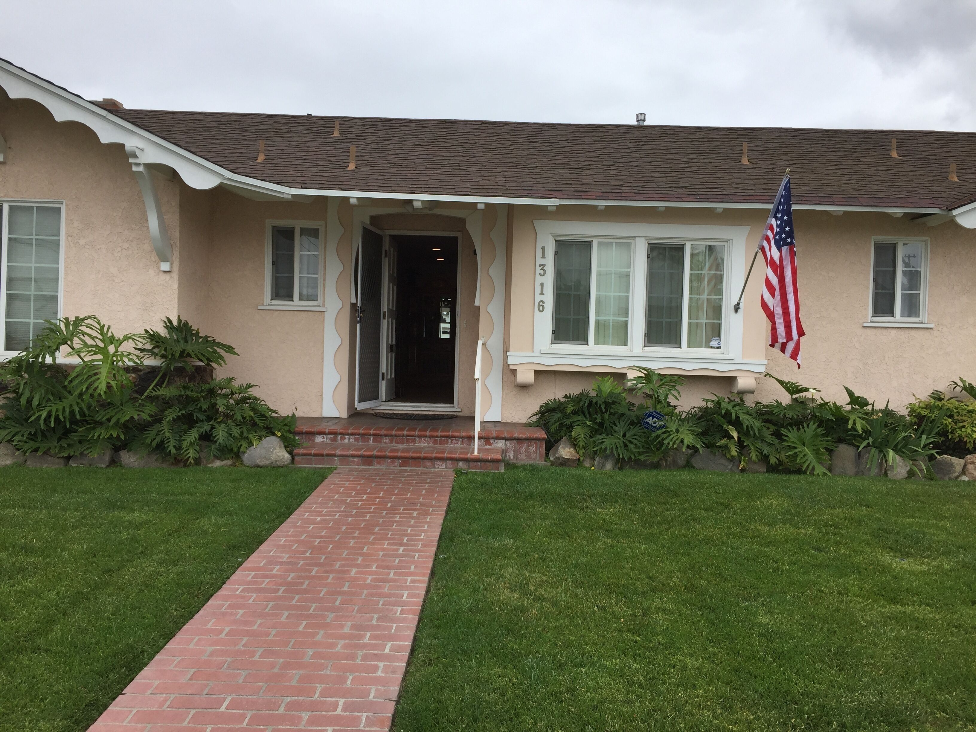 A house with a brick pathway leading to a door, an American flag, and a mailbox.