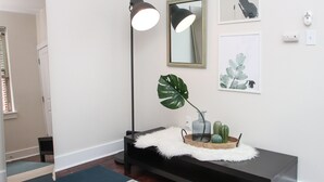 Een moderne entree met een bankje, een vloerlamp, een spiegel en wanddecoratie.