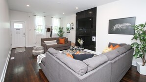 Een moderne woonkamer met een grijze modulaire bank, een bijzettafeltje en een zwarte haard.