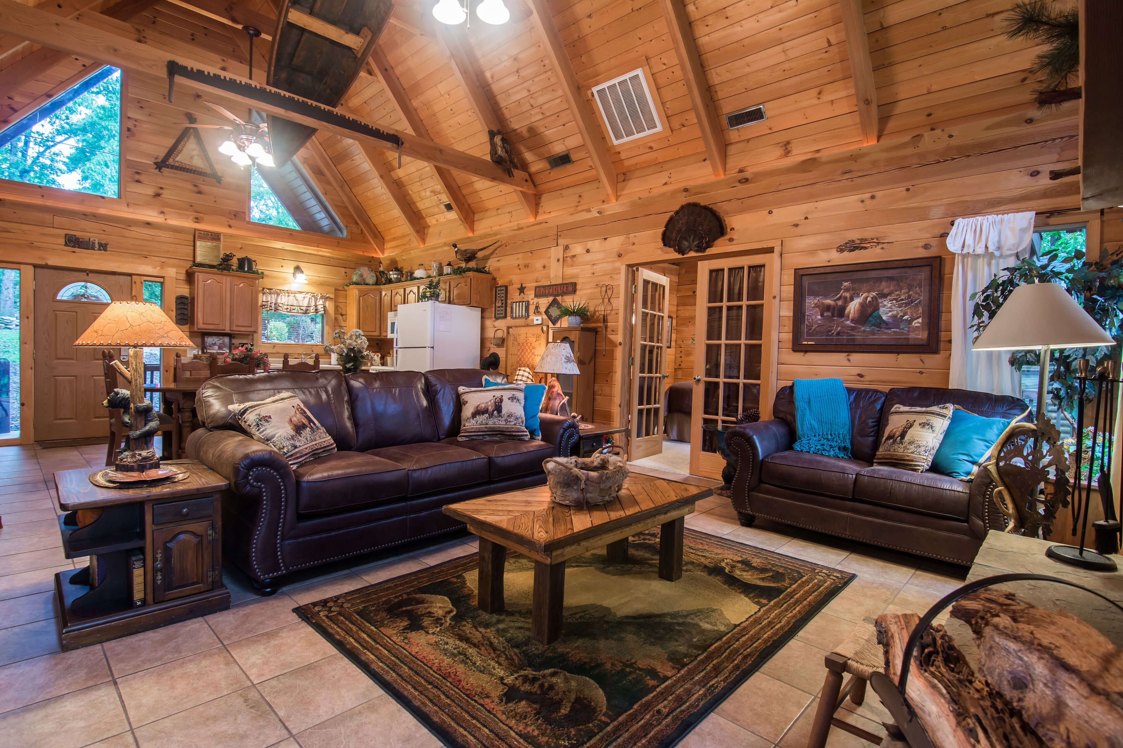 A cozy log cabin interior with a living room featuring two sofas, a coffee table, and a fireplace.