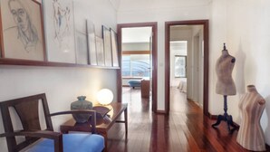 Un couloir avec un plancher en bois, un canapé bleu, une lampe et un mannequin.