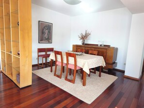 Ein Essbereich mit Holztisch, Stühlen, Teppich und Schrank.