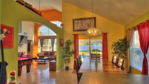 A dining area with a long table, chairs, a chandelier, and a view through a glass door to an outdoor space. - Adventure Villa - Heated Pool & Spa - Themed Rooms - Min. to Disney - Game room (Davenport)
