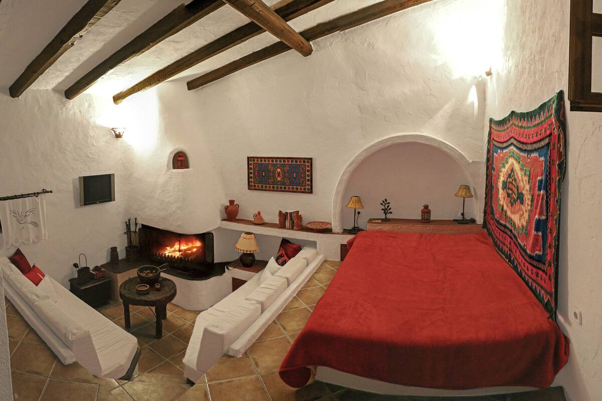 A cozy room with a fireplace, white furniture, and a red bedspread.
