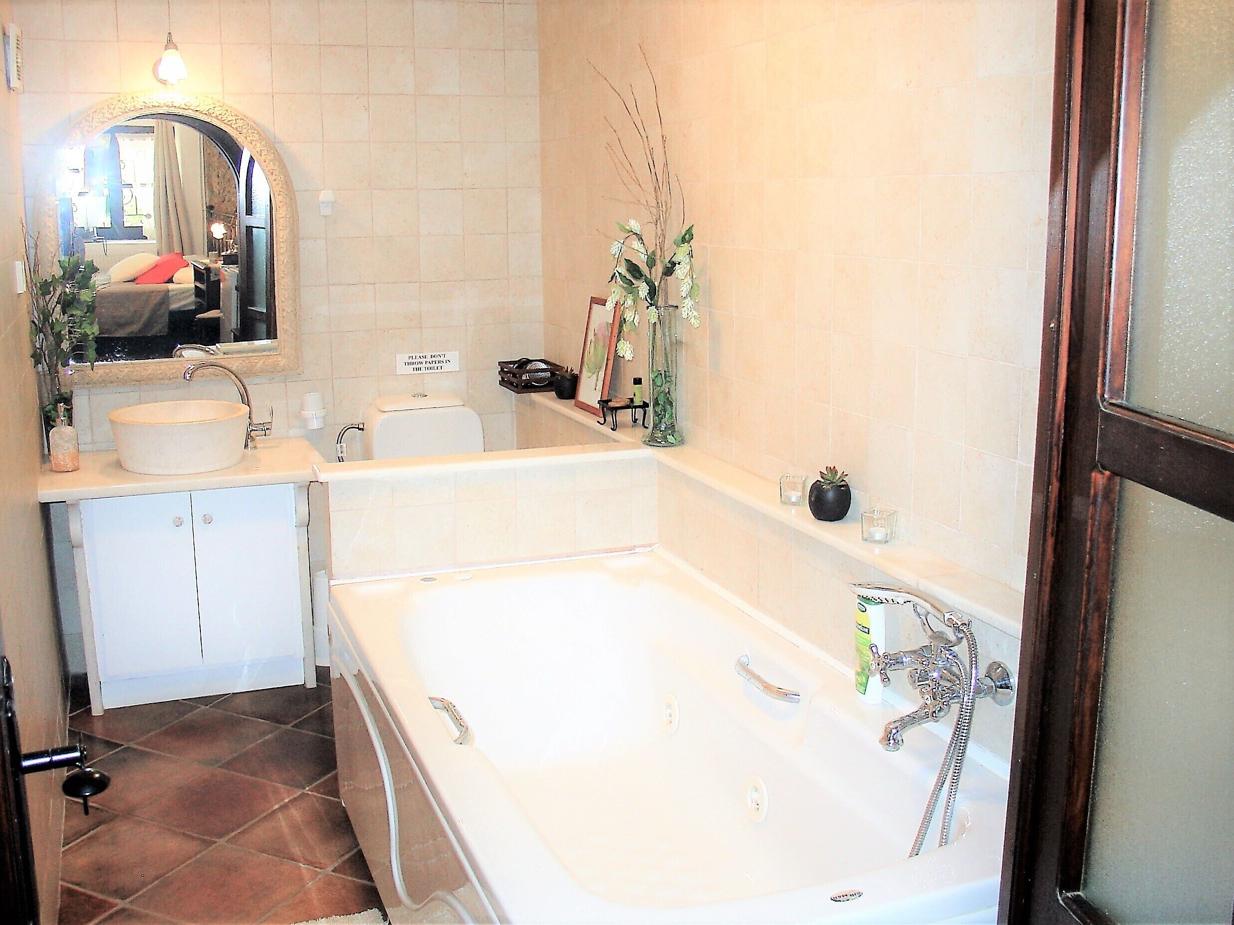 A bathroom with a bathtub, sink, mirror, and toilet.