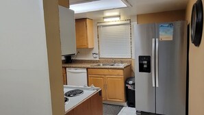A compact kitchen with a refrigerator, stove, sink, and wooden cabinets. - Cozy Condo For Rent In Melbourne Florida.  5 Miles from the beach (Melbourne)