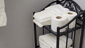 A black metal shelf with white towels and toilet paper in a bathroom. - Cozy Condo For Rent In Melbourne Florida.  5 Miles from the beach (Melbourne)