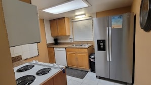A compact kitchen with a stove, sink, and refrigerator. - Cozy Condo For Rent In Melbourne Florida.  5 Miles from the beach (Melbourne)