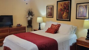 A hotel room with a large bed, two bedside tables, a TV, and artwork on the walls. - Cozy Condo For Rent In Melbourne Florida.  5 Miles from the beach (Melbourne)