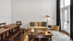 A living room with a wooden dining table, benches, a sofa, and a coffee table with decorative items.