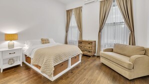 A bedroom with a bed, nightstand, dresser, and a sofa.