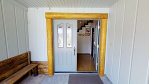 A wooden-framed door with a bench to the left, leading to a hallway with a staircase. - Expansive Lake View Home1 mile from the Village w/ Hot tub & Game Rm VRR20250487 (Big Bear Lake)