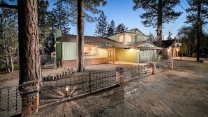 A two-story house with a front porch, a garage, and a fenced yard. - Expansive Lake View Home1 mile from the Village w/ Hot tub & Game Rm VRR20250487 (Big Bear Lake)