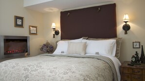 A neatly arranged bedroom with a large bed, a fireplace, and wall-mounted lamps. -   Charming Self-Contained Guest Cottage in Old Town Niagara-on-the-lake. (Niagara on the Lake)