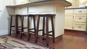 A kitchen with a bar stool area, wooden stools, and a patterned rug. -   Charming Self-Contained Guest Cottage in Old Town Niagara-on-the-lake. (Niagara on the Lake)