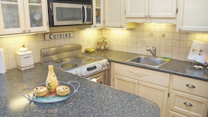 A kitchen with white cabinets, a microwave, a stove, and a sink. -   Charming Self-Contained Guest Cottage in Old Town Niagara-on-the-lake. (Niagara on the Lake)