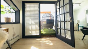 A room with a large open door leading to an outdoor area with a swing chair and a hanging chair.
