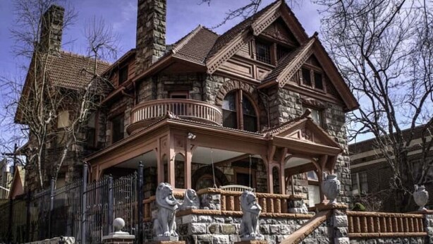 A large, historic stone building with a prominent balcony and ornate architectural details.